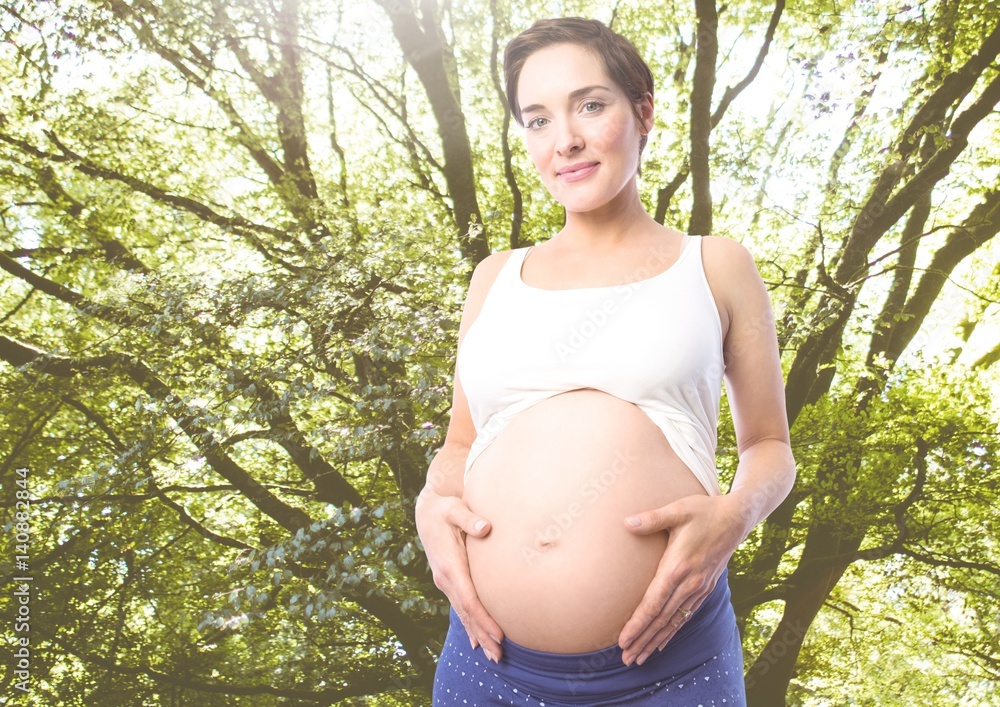 Portrait of pregnant woman standing against greenery