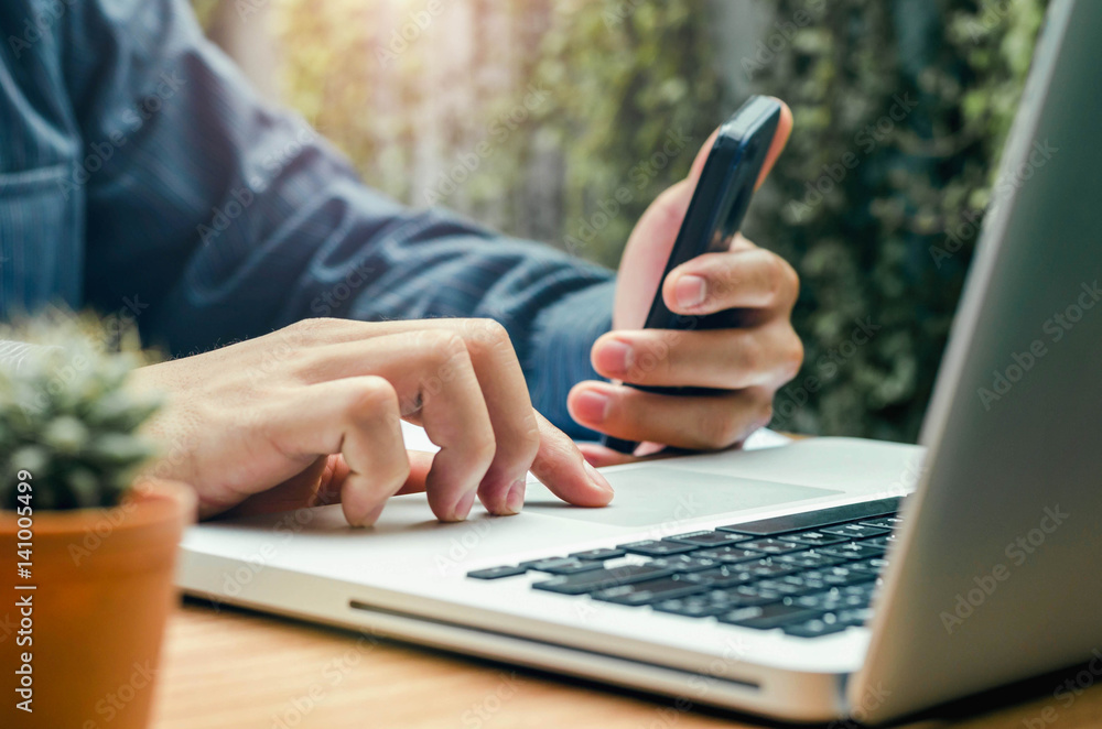 Image of business person using laptop at desk and moblie phone