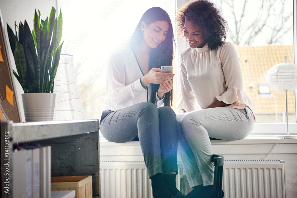 Smiling young women texting a phone message