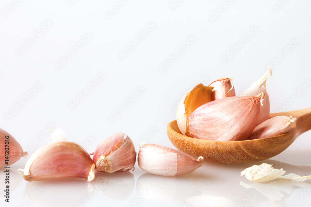 Close up garlic in a wooden spoon on white background