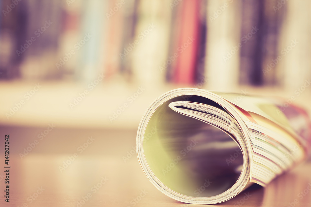 Close up edge of colorful magazine stacking roll with  blurry bookshelf background for bublication a