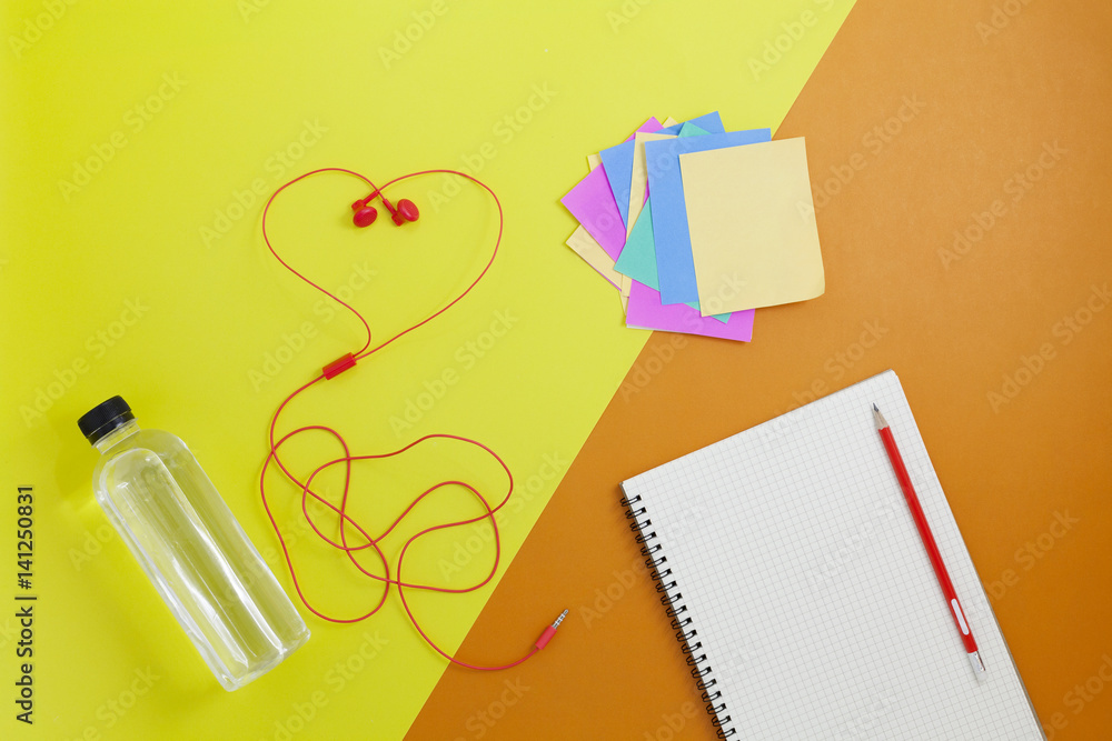 close up of water bottle and red earphones and paper note on beautiful retro pastel color paper back