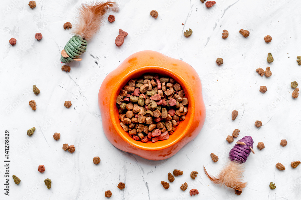 dry cat food in bowl on stone background top view