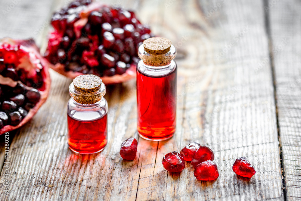 sliced pomegranate and extract in glass on wooden background