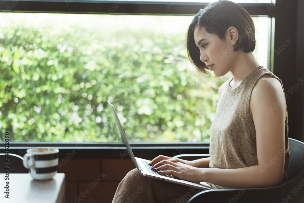 Asian women using a notebook computer in the cafe.