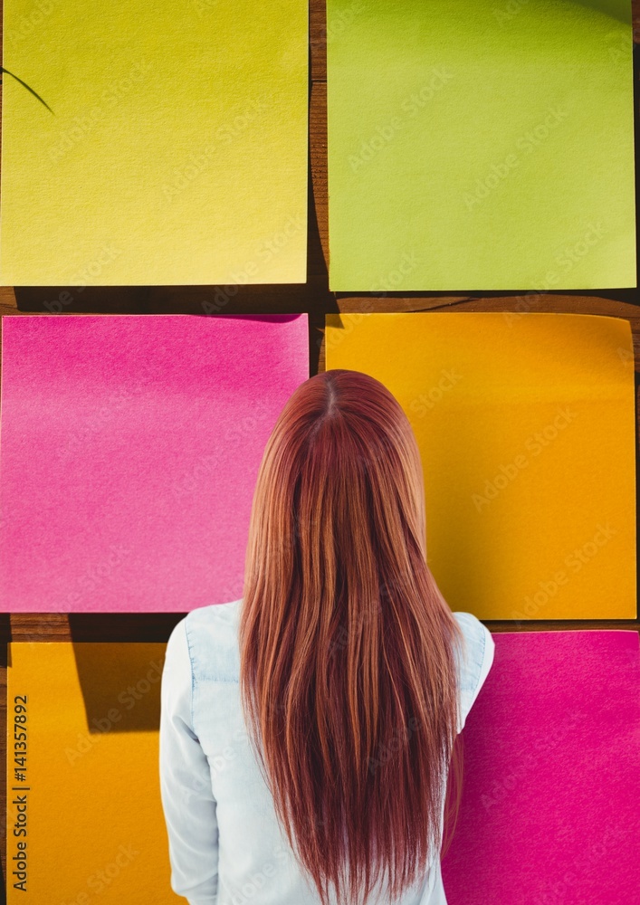 Rear view of woman looking at large multicolored sticky note