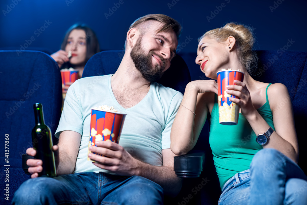 Lovely couple watching film sitting together with popcorn in the cinema