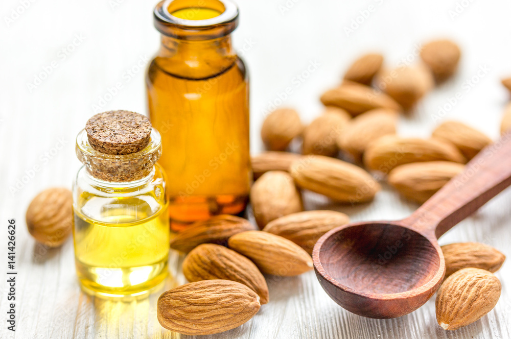 cosmetic and therapeutic almond oil on light wooden background