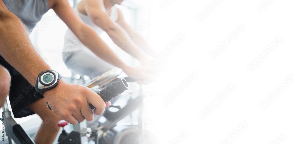 Midsection of men working on exercise bikes