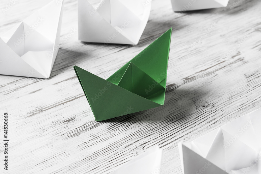 Business leadership concept with white and color paper boats on 