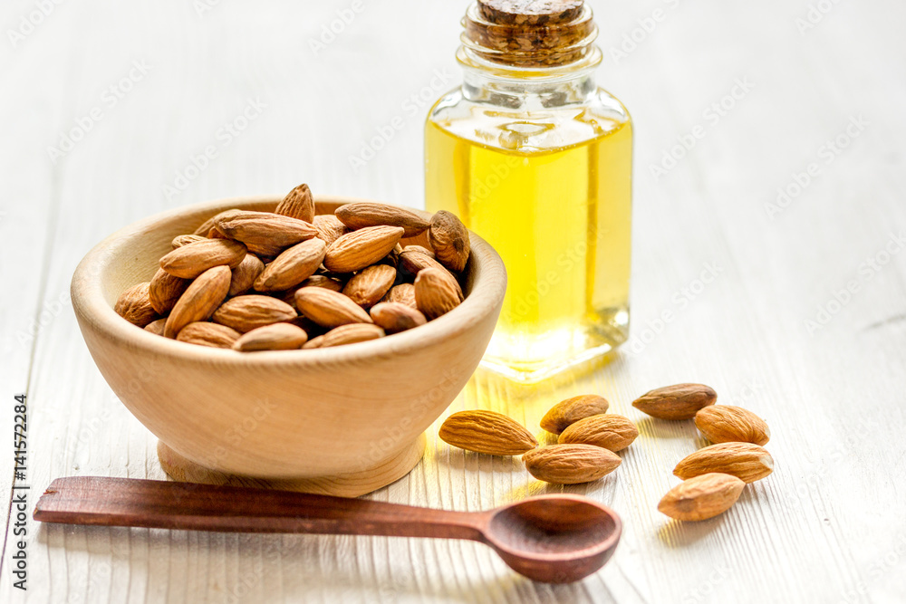 cosmetic and therapeutic almond oil on light wooden background