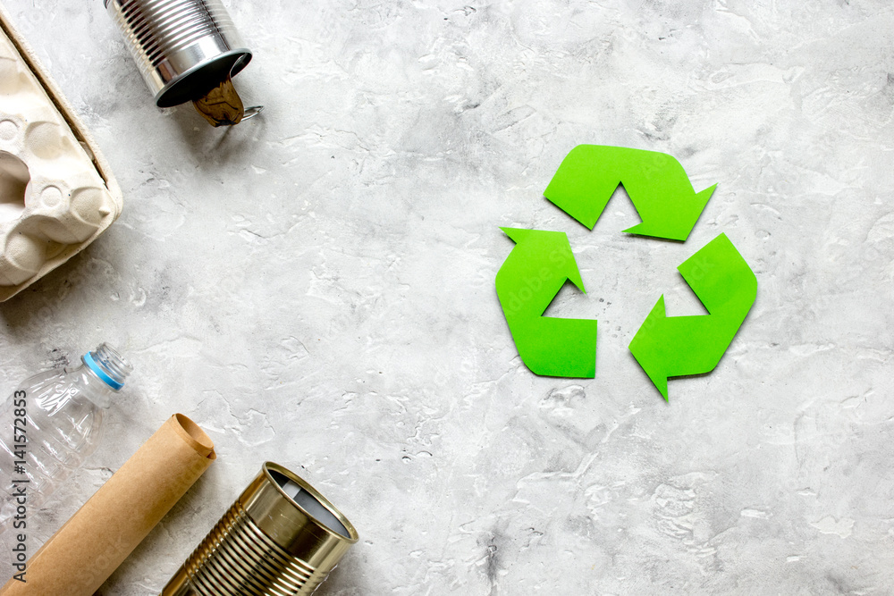 waste recycling symbol with garbage on stone background top view mockup