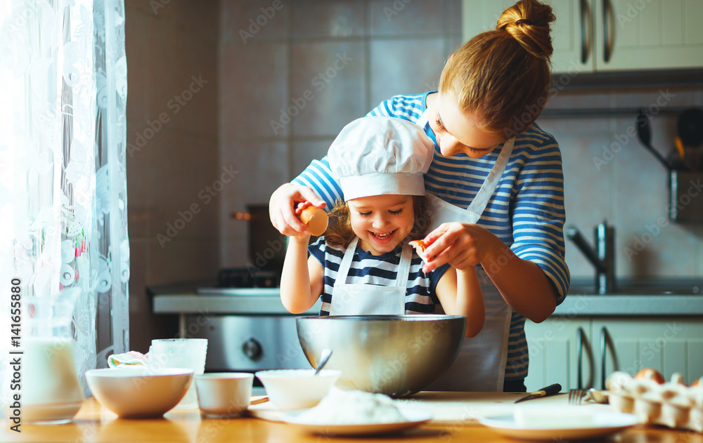 happy family in kitchen. mother and child preparing dough, bake cookies