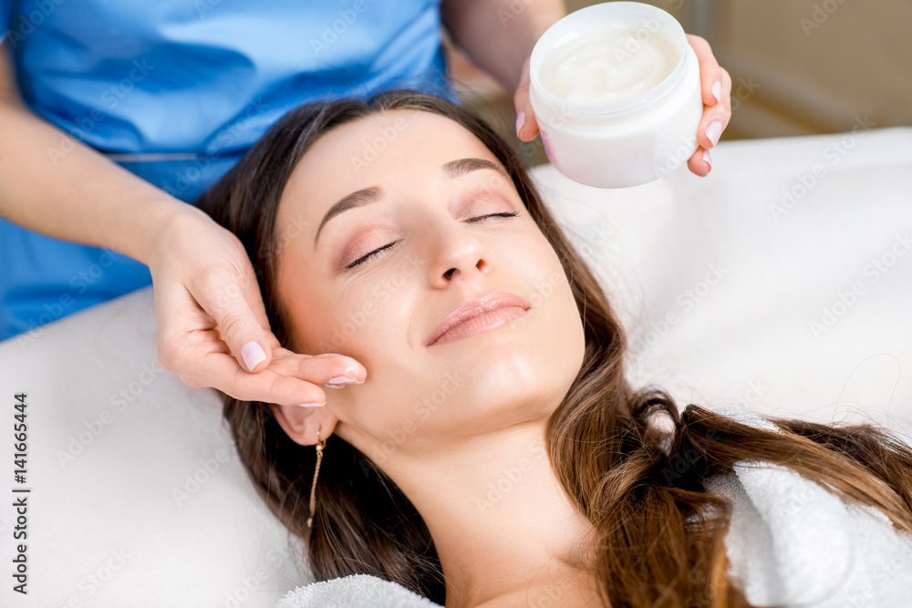 Cosmetologist applying facial cream to the client in the cosmetology office