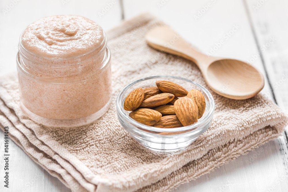 body scrub with almonds for body care on light table background