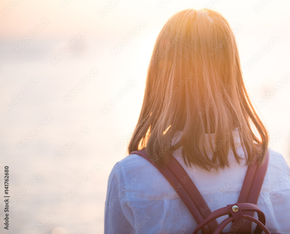 年轻女子站在海边看太阳