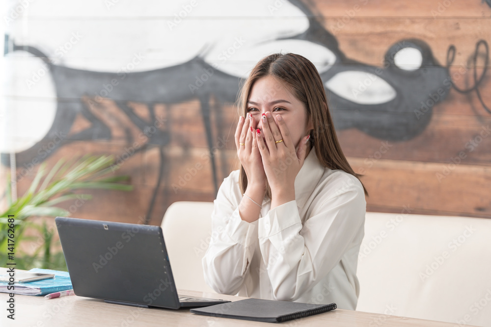 Portrait of surprised happy and excited young business woman cheerful and glad with a laptop