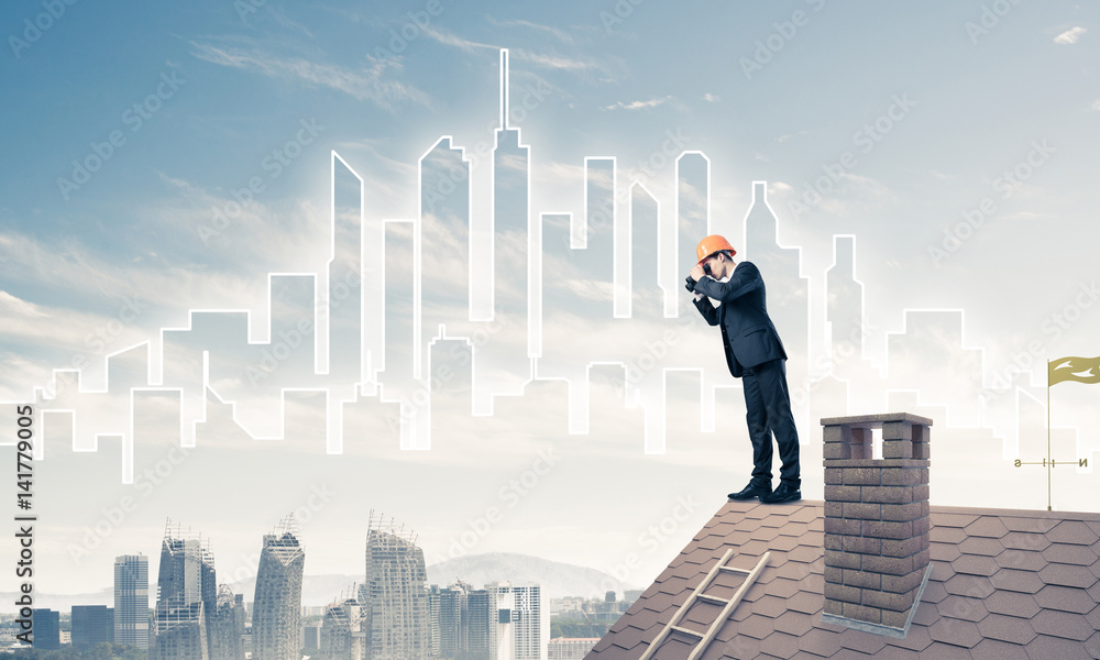 Engineer man standing on roof and looking in binoculars. Mixed m