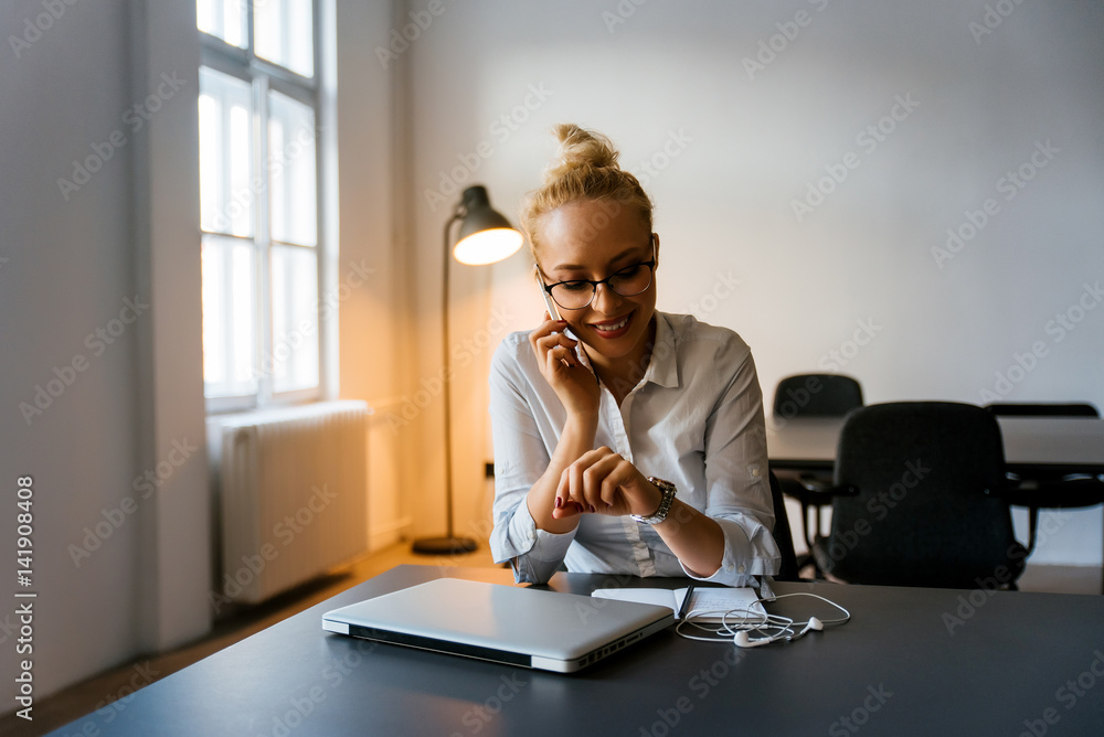 一位面带微笑的女商人看着手表打电话的照片