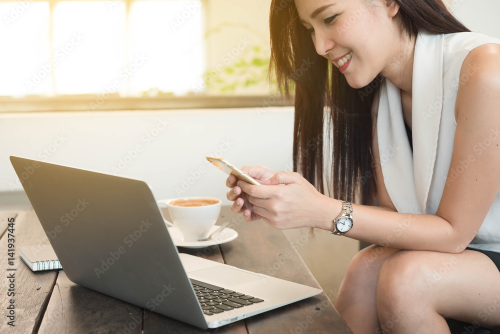 beautiful young woman use smart phone in coffee shop with laptop on table