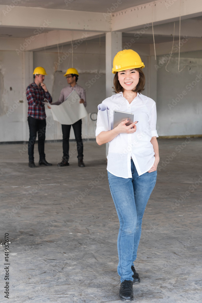 Asian Construction engineer smile wear yellow safety helmet with blue print of construction plan and