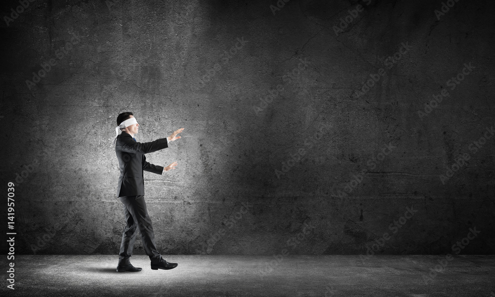 Business concept of risk with businessman wearing blindfold in empty concrete room