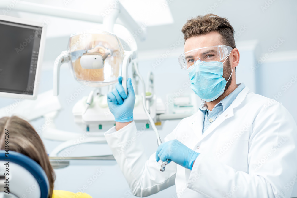 Portrait of a dentist in mask and protective glasses during the dental surgery