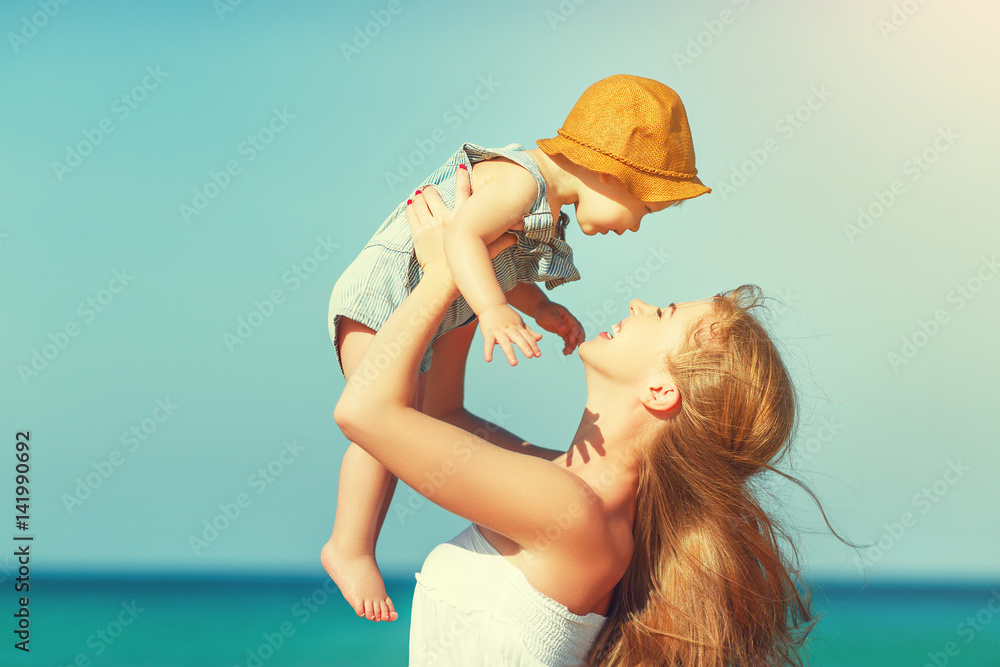 happy family mother with baby son walks by ocean on beach in summer.