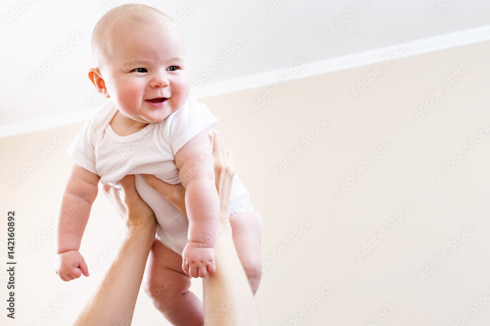 Happy infant baby girl being held up in the air