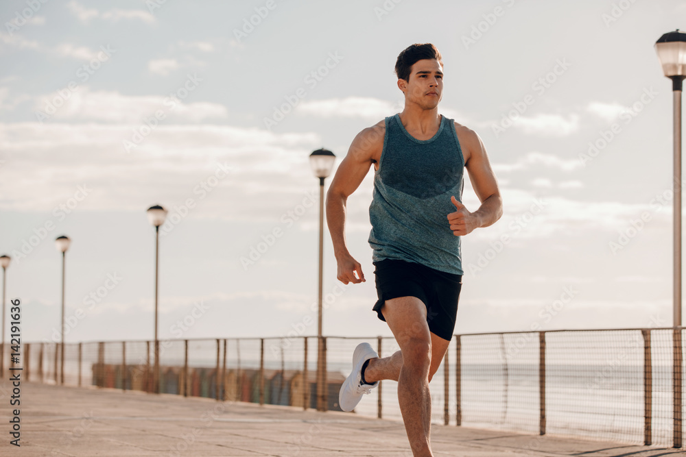 Fit young man running on seaside promenade