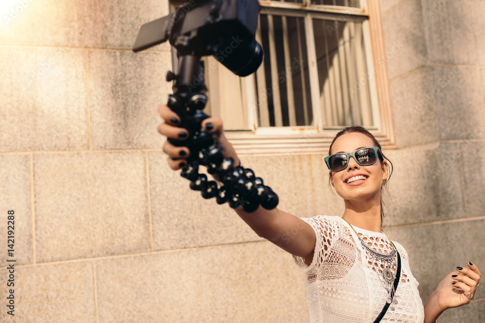 Young tourist recording selfie video while walking in the street