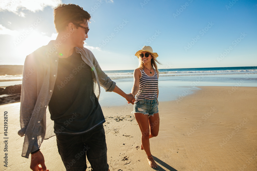 浪漫的年轻情侣牵手在海滩上漫步