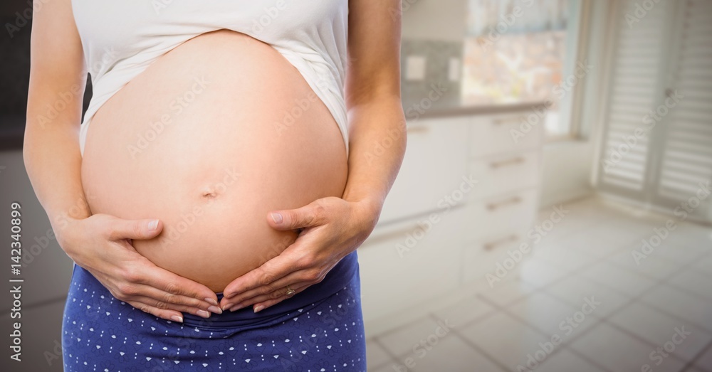 Pregnant woman mid section in blurry kitchen