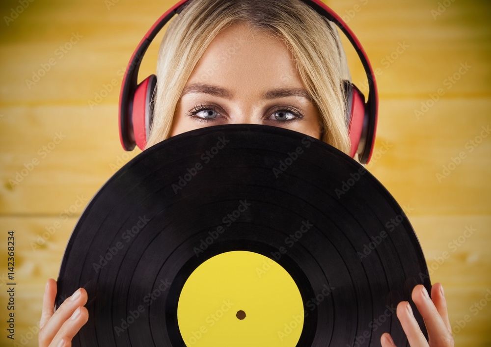 Woman with headphones and record against yellow wood panel