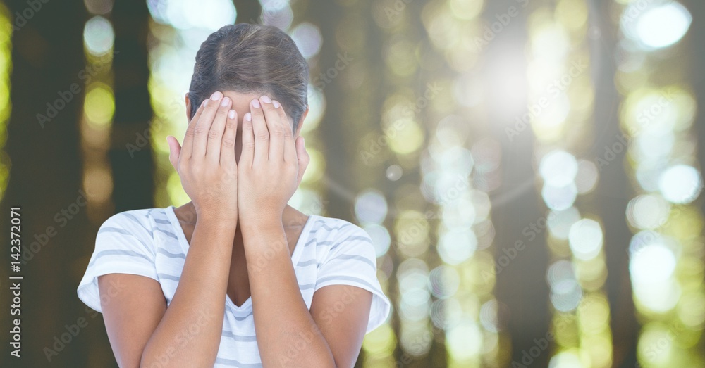 Sad girl hiding in hands in woods forest