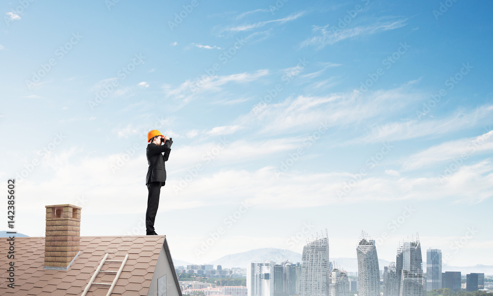 Engineer man standing on roof and looking in binoculars. Mixed media