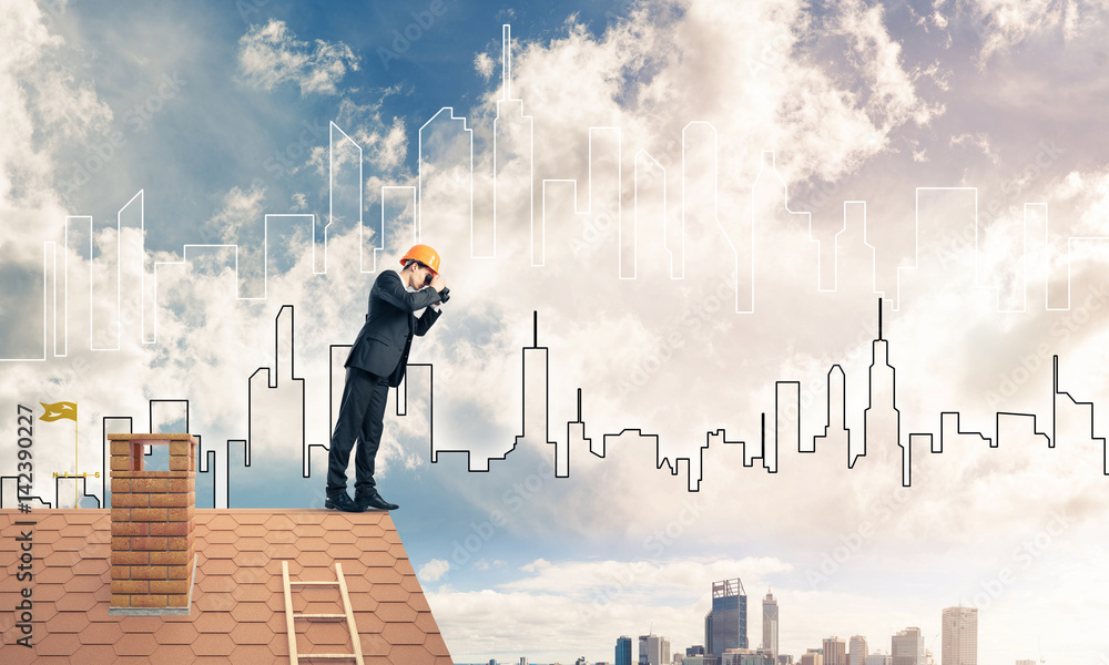 Engineer man standing on roof and looking in binoculars. Mixed m