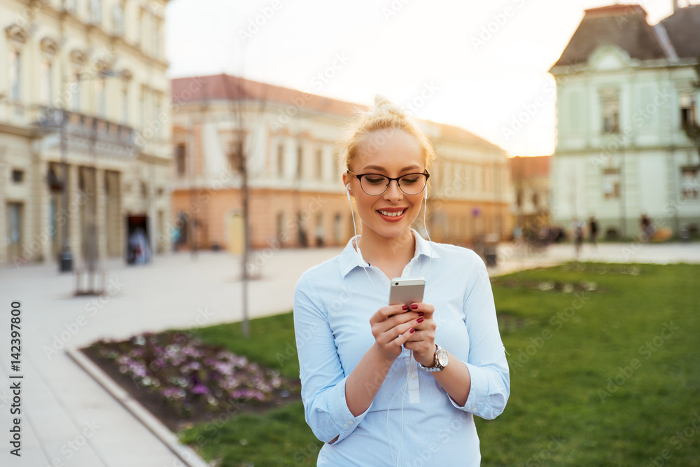 Blonde girl texting in the city