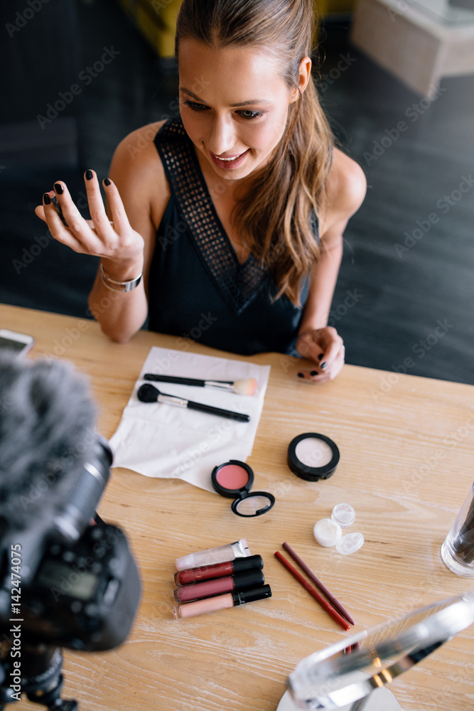 Young female vlogger recording a make-up video for her vlog.