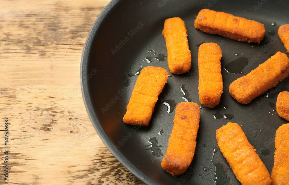 Pan with cheese sticks on wooden background