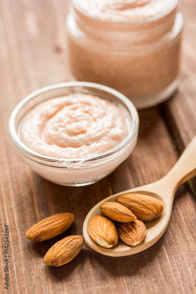 spa concept with almond nuts and scrub on wooden background