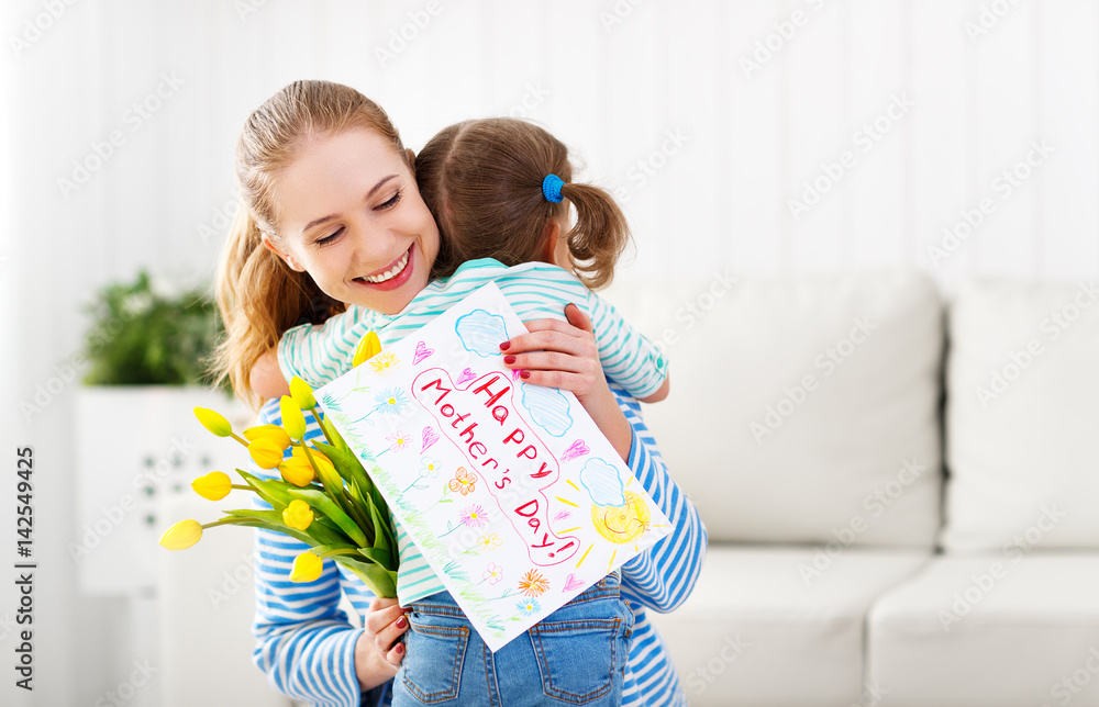 Happy mothers day! Child daughter congratulates moms and gives her a postcard and flowers