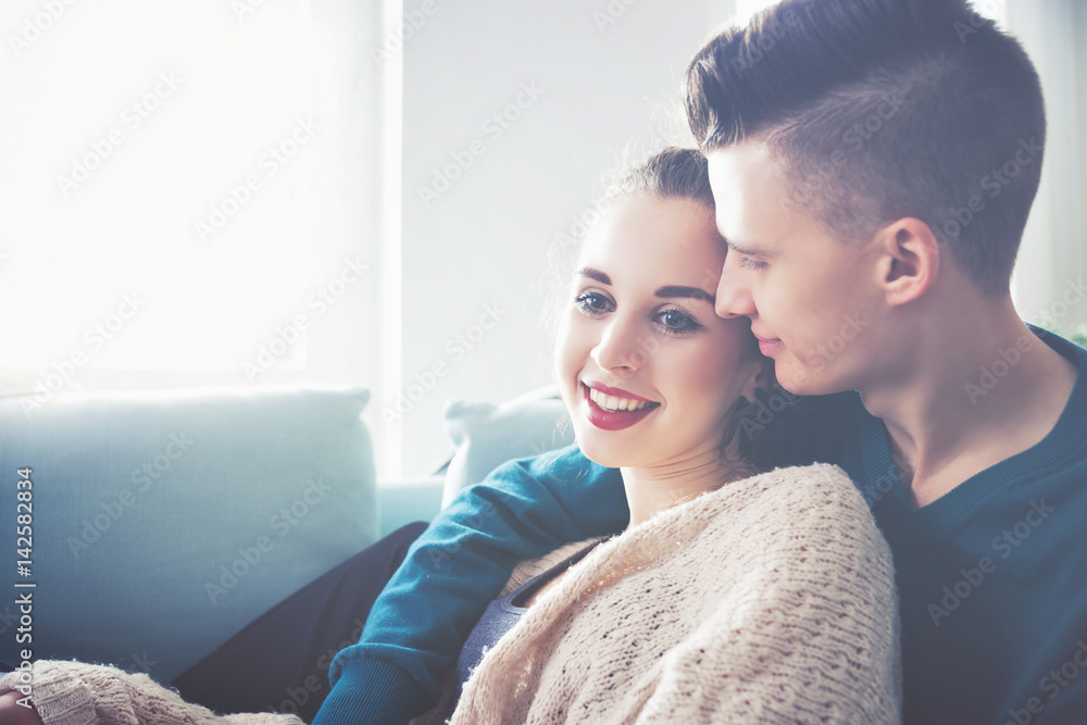 Loving young couple hugging and lying on sofa at home