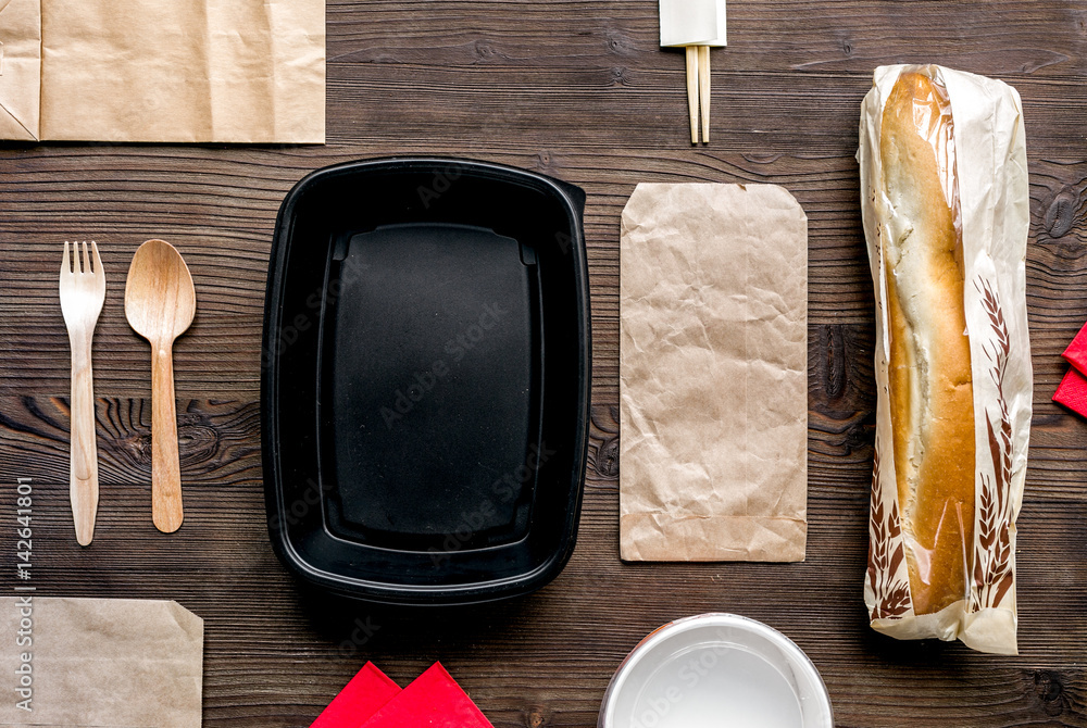 food delivery with paper bags and sandwich on wooden background top view