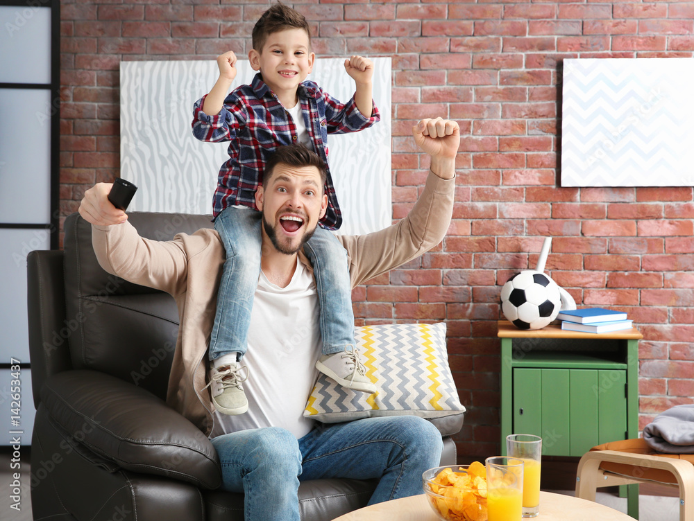 Father and son watching football on TV at home