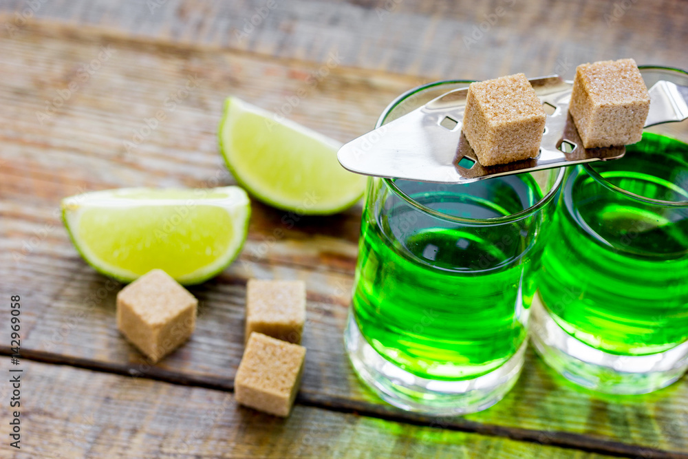 absinthe in glass with lime slices on wooden background