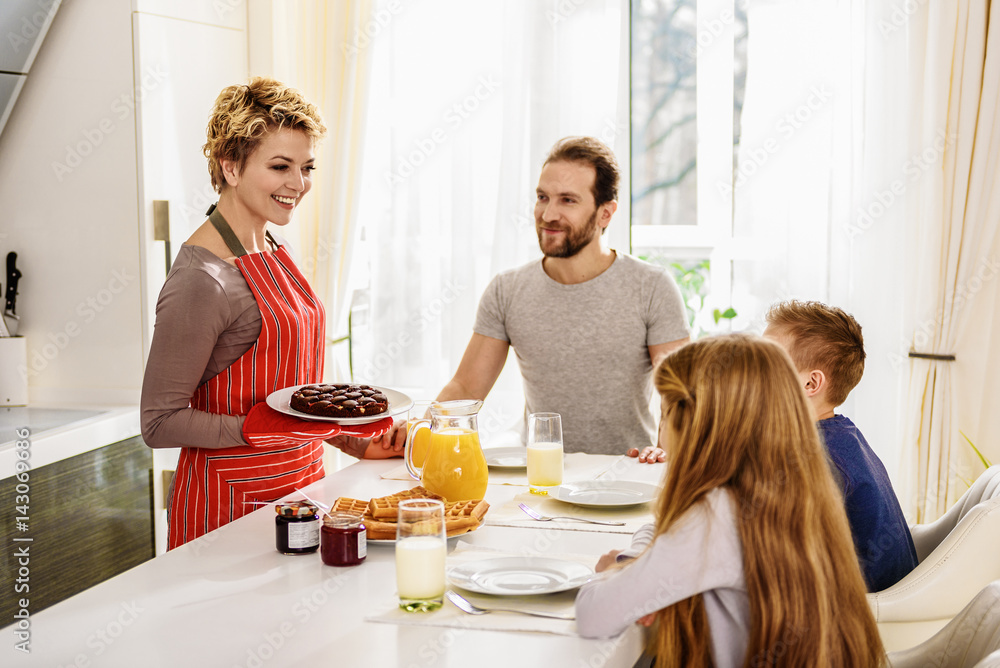 Joyful parents and kids enjoying morning in kitchen