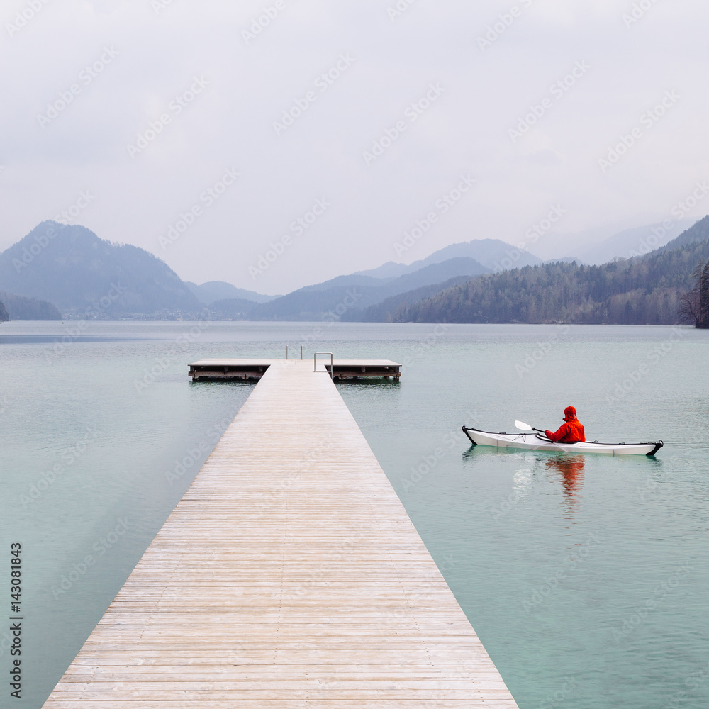 Beautiful lake scene with kayak and wooden landing stage on a cloudy moody day in the Alps, Lake Fus