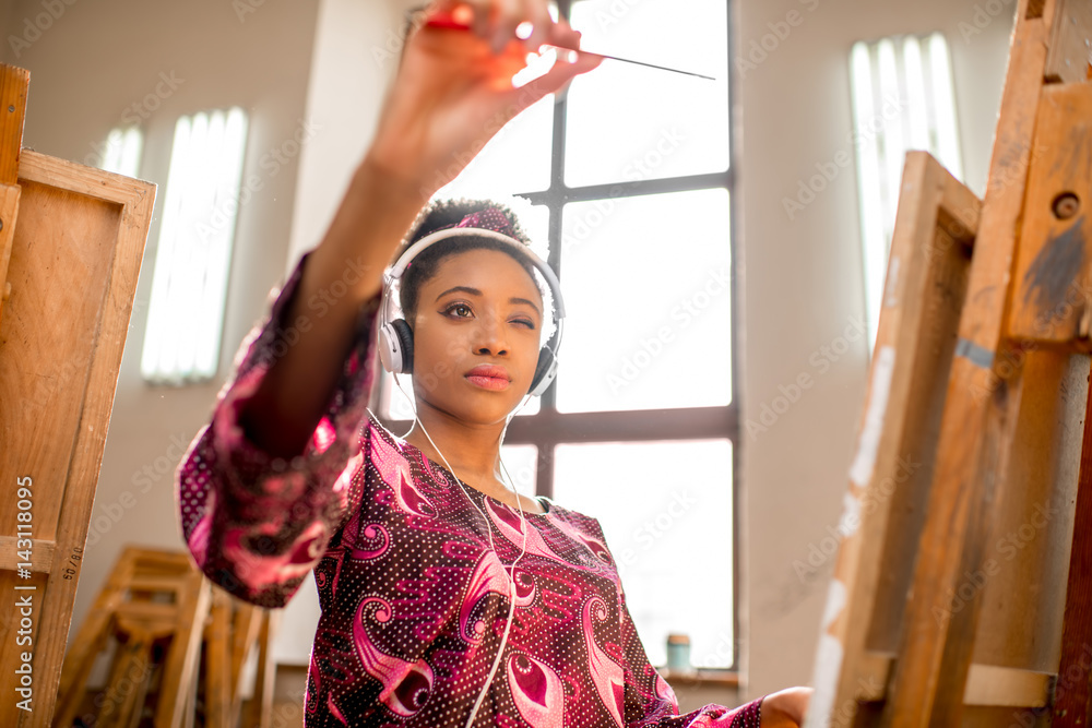 Young creative african ethnicity student drawing on the easel at the university studio