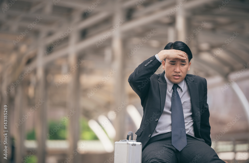 商人伤心烦恼累了，背着黑袋子坐在街上